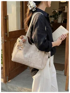 Détail du sac cabas beige avec texture grainée et décoration de charme d'ours en peluche