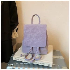 Detail of a purple textured faux leather backpack with flap and drawstring closure