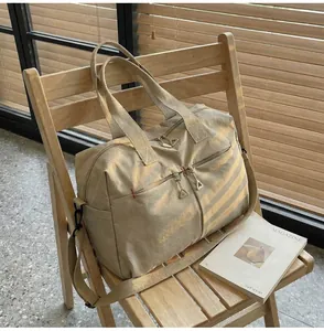 Dettaglio di borsa da viaggio in tela beige con cerniere in metallo su sedia in legno