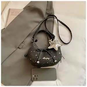 Detail van zwarte halvemaanvormige crossbodytas met sterren en zilveren strik