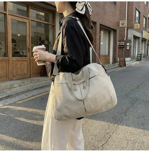 Grande borsa da viaggio in tela color crema indossata a tracolla per sport