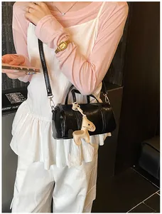 Dettaglio della borsa Boston nera lucida con ciondolo a cavallo beige e tracolla
