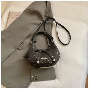 Detail van zwarte hobo-tas met strik die het compacte formaat met mobiel toont