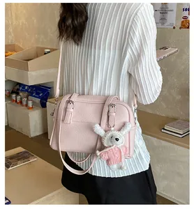 Pink lychee texture crossbody bag with cute rabbit plush charm shown on a model