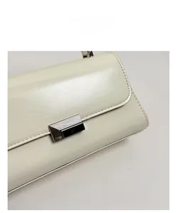 Macro shot of cream leather bag flap featuring a minimalist rectangular metal clasp