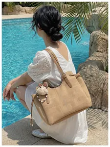 Sac cabas en daim kaki avec coutures blanches et breloque ours près d'une piscine