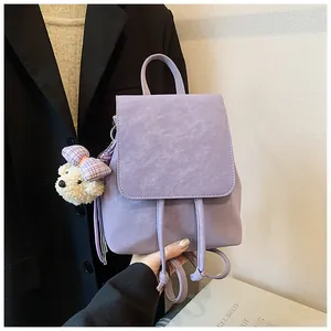 Detail of light purple pebbled leather backpack with a cute plush bear charm accessory