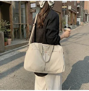 Dettaglio di una grande borsa da viaggio in tela beige con tracolla regolabile in città