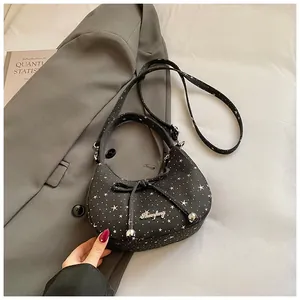 Detail van zwarte crossbodytas met sterrenpatroon, strik en metalen merklogo-accent