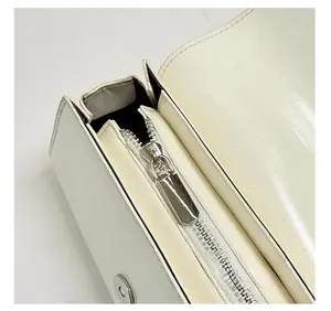 Detail of silver zipper and magnetic clasp on a white faux leather crossbody bag
