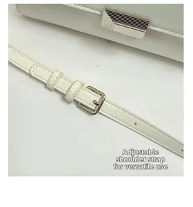 Detail of white leather shoulder bag featuring multi-hole adjustable strap and silver buckle
