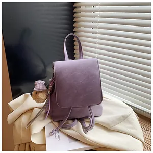 Detail of purple matte leather backpack featuring a cute bear plush pendant and rounded flap