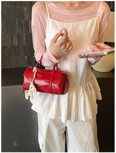 Dettaglio borsa Boston rossa lucida con ciondolo a cavallo su un outfit alla moda