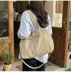 Dettaglio della borsa da viaggio in tela con tracolla regolabile davanti a un caffè
