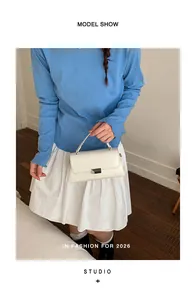 Chic cream leather rectangular handbag with silver metal buckle shown on a model