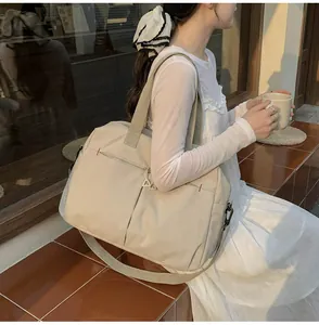 Borsa da viaggio capiente in tela beige con tracolla rimovibile mostrata in uso esterno