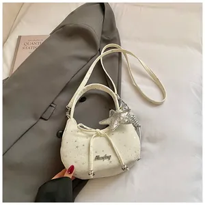 Detail van witte halve maan tas met sterrenprint, strik en een zilveren sterhanger