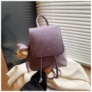 Detailed view of purple mini PU leather backpack with a plush bear charm on side