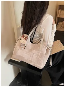 Détail d'un sac cabas beige texturé avec une jolie peluche de chien et des perles