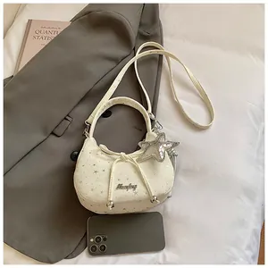Detail van de crème mini-crossbodytas met zilveren sterrenprints en strikdecoratie