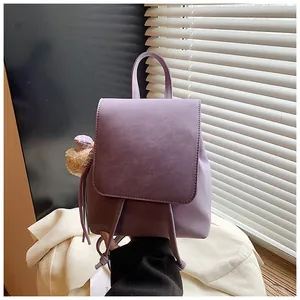 Detail of purple faux leather backpack with drawstring closure and a plush bear charm