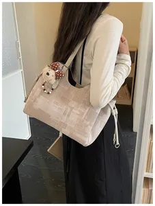 Détail du sac cabas en jacquard beige avec motifs abstraits et breloque ourson