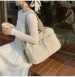Dettaglio borsa da viaggio in tela con tasche zip, cuciture rosse e tracolla rimovibile