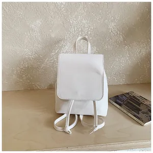 Minimalist white PU leather backpack with flap closure on a wooden surface