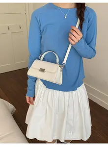 Detail of white rectangular crossbody bag with silver metal lock and top handle