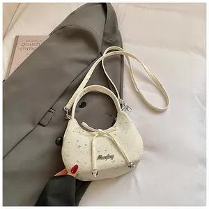Detail van de crème halve maan tas met zilveren sterren, strik en metallic kralen accenten