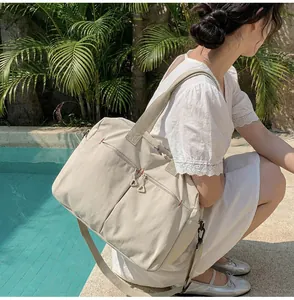 Dettaglio della grande borsa da viaggio in tela beige con tasche multiple e tracolla rimovibile