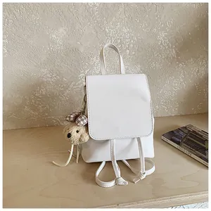 Detail of white PU leather mini backpack with cute teddy bear charm and adjustable straps