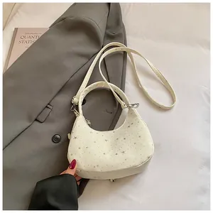 Detail van witte halvemaantas met zilveren sterren en metalen gesp op een grijze blazer