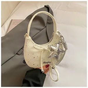 Detailopname van crème canvas tas met sterren en een hanger met zilveren lovertjes
