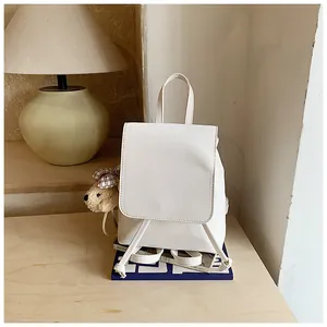 Detail of white PU leather backpack with drawstring closure and cute plush bear charm
