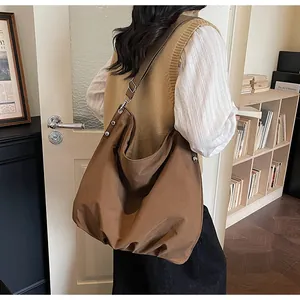 Detail van de grote donkerbruine hobo-tas met brede riem en zilveren gesp-sluitingen
