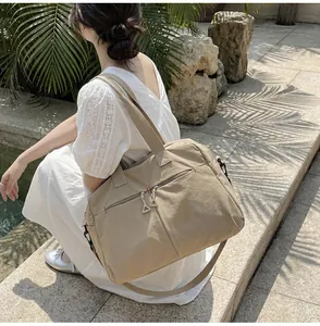 Dettaglio borsa da viaggio in tela beige con tasche frontali e tracolla regolabile
