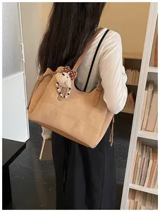 Détail d'un grand sac cabas beige avec texture tressée et pendentif ours mignon