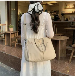 Grande borsa da viaggio in tela beige con tracolla regolabile in un ambiente esterno