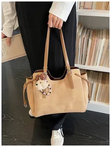 Détail d'un sac cabas kaki texturé avec un ours en peluche et un ornement de perles