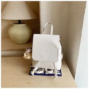 Detail of a white mini PU leather backpack with a plush bear charm and rope straps