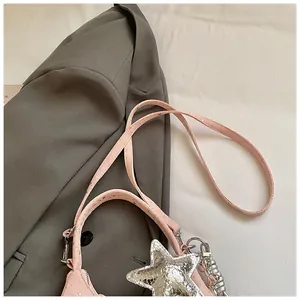 Detail van de roze crossbodytas met zilveren sterhanger en sterrenriem