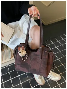 Gros plan d'un cabas marron rétro avec texture géométrique et pendentif ours en peluche