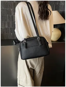 Detailed view of black litchi texture leather handbag with silver metallic buckle
