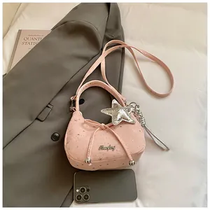 Detail van roze handtas met sterrenprint, strikje en zilverkleurige sterrenhanger