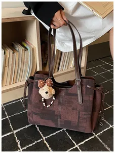 Gros plan d'un grand sac cabas en toile imprimée marron avec charm ours en peluche