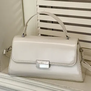 Elegant cream glossy handbag with silver metal clasp shown against a white shutter backdrop