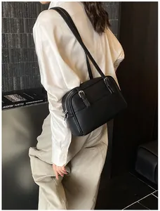 Close-up of black lychee grain leather crossbody bag with silver buckles and zipper