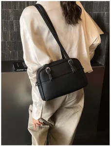 Detail of black lychee grain texture and silver buckle straps on a crossbody bag