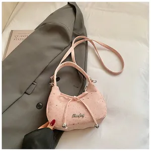 Detail van roze tas met sterpatronen, metalen logo en schouderband op een blazer